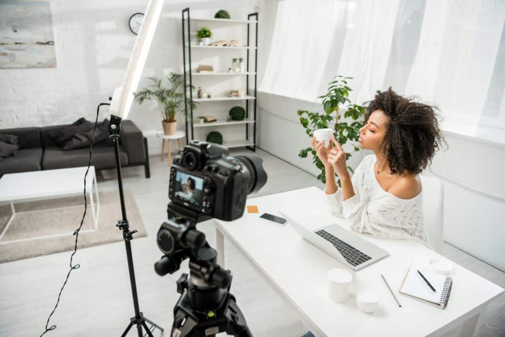 influenciador afro-americano segurando recipiente com creme cosmético perto de digital